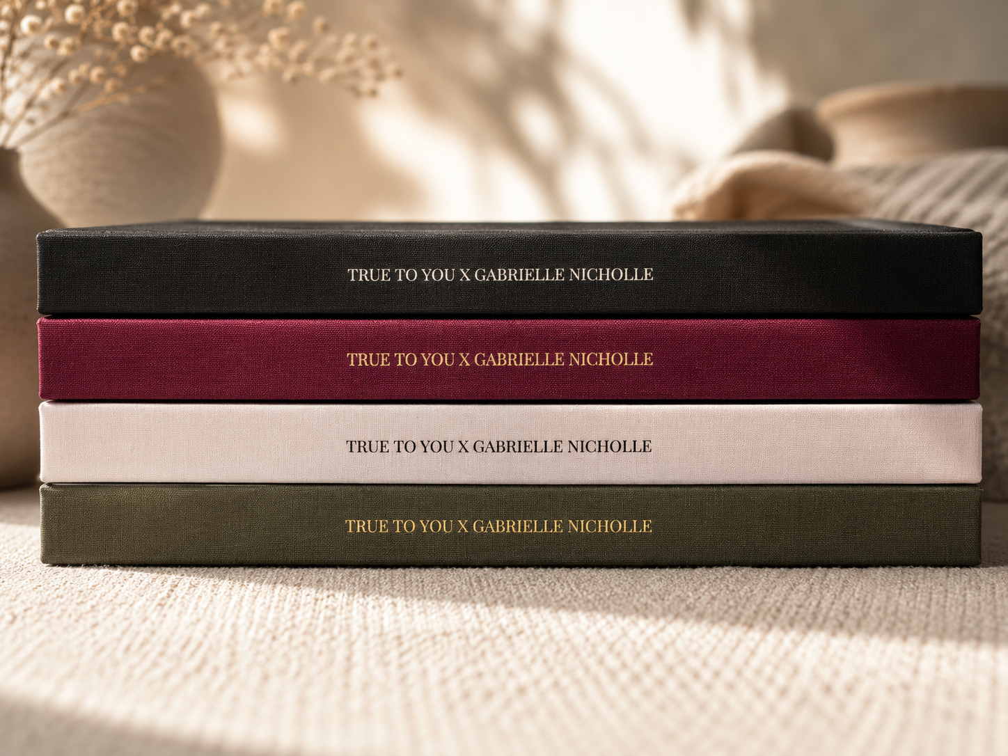 A stack of four True To You journals photographed from the side, spines reading True To You x Gabrielle Nicholle